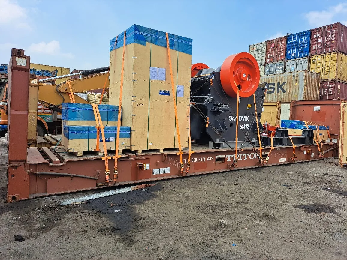 Crusher and crated machinery lashed on a flat rack container