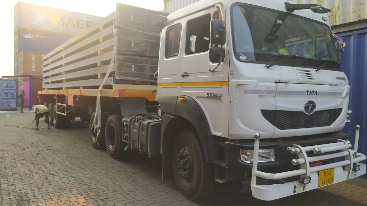 Truck with a flatbed trailer loaded with panels in a container yard